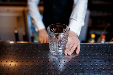 elegant young male barman prepares a delicious cocktail at the bar