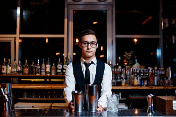 elegant young male barman prepares a delicious cocktail at the bar