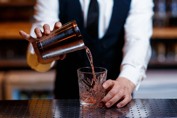 barman at work. A young bartender works with a shaker. Prepares delicious alcoholic cocktails