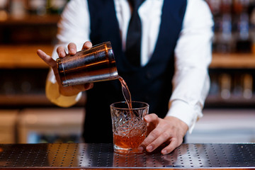 barman at work. A young bartender works with a shaker. Prepares delicious alcoholic cocktails