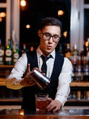 barman at work. A young bartender works with a shaker. Prepares delicious alcoholic cocktails