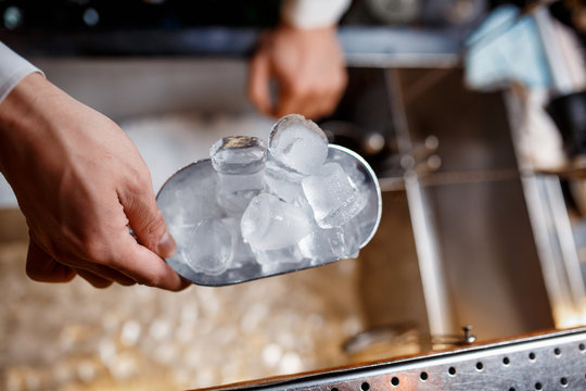 bartender scoops up ice for making alcoholic cocktails. close-up - Powered by Adobe