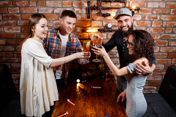 friends with smiles on their faces at the bar have fun, drink cocktails, cheks in glasses