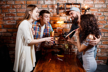 friends with smiles on their faces in the bar have fun, drink cocktails, clink glasses. friendly company celebrate a birthday