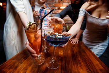 friends with smiles on their faces in the bar have fun, drink cocktails, clink glasses. friendly company celebrate a birthday