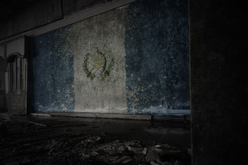 painted flag of guatemala on the dirty old wall in an abandoned ruined house.