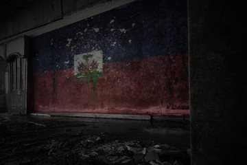 painted flag of haiti on the dirty old wall in an abandoned ruined house.