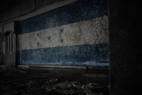 painted flag of honduras on the dirty old wall in an abandoned ruined house.
