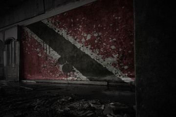 painted flag of trinidad and tobago on the dirty old wall in an abandoned ruined house.