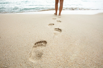 Woman Walking On Beach Leaving Footprints In The Sand