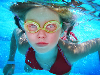 Girl in goggles swim and dive under water. Portrait of kids face and body float in pool.