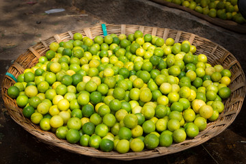 basket full of green and yellow  lemons and limes on a food market in the south of india