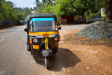 tuk tuk taxi driving  on a sunny day in the streets in the south of of india