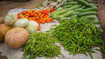 mixed vegetables like pumpkins, tomatoes, chili peppers, white cabbage and beans at a roadside market in the south of india.