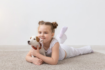 people, children and pets concept - little child girl lying on the floor with cute puppy Jack Russell Terrier