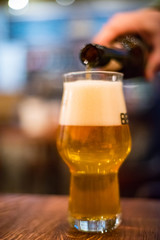 pouring beer from bottle into glass at bar
