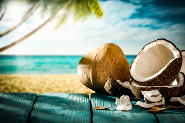 Fototapeta na wymiar Coconut on blue wooden table and summer landscape of beach 