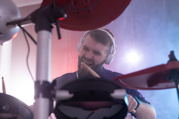 Obraz premium Hobbies, music and people concept - emotional guy playing on electronic drums on the stage
