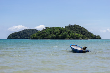 Fototapeta na wymiar Mountain island over the sea with small boat floating over the sea and bright sky in background in the afternoon at Koh Mak Island in Trat, Thailand.