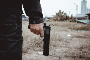 Killer holding a gun side him , cropped shot of man holding gun in hand.