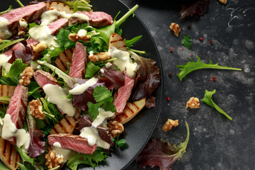 Grilled Beef Steak salad with pears, walnuts and greens vegetables and blue cheese sauce. healthy food.