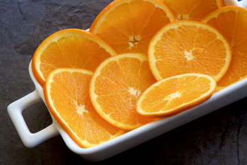 Slices of citrus orange fruit on a white dish.
