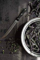 Green and black fresh organic sliced beans on isolated background with blue and white cloth and...