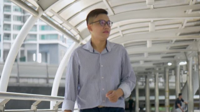 Slow motion portrait asian businessman walking and looking at camera on street urban city.