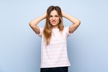 Young woman over isolated blue background frustrated and takes hands on head