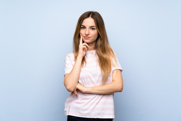 Young woman over isolated blue background Looking front