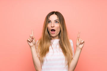 Obraz premium Young woman over isolated pink wall pointing with the index finger a great idea