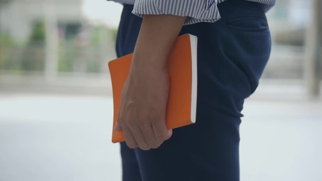 Close up caucasian businessman hand holding a book on the street urban city.