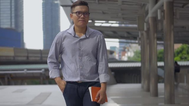 Portrait caucasian businessman hand holding a book walking on the street urban city.