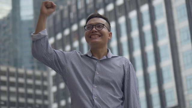 Portrait handsome asian businessman after a working have success and achievement standing looking around urban city. Slow motion low angle shoot.