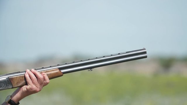 Man firing from over and under shotgun training skeet shooting in slow motion   