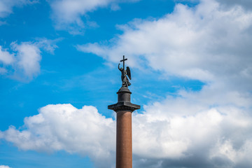 Fototapeta na wymiar Angel on the Alexandrian pillar in St. Petersburg against the blue sky with white clouds