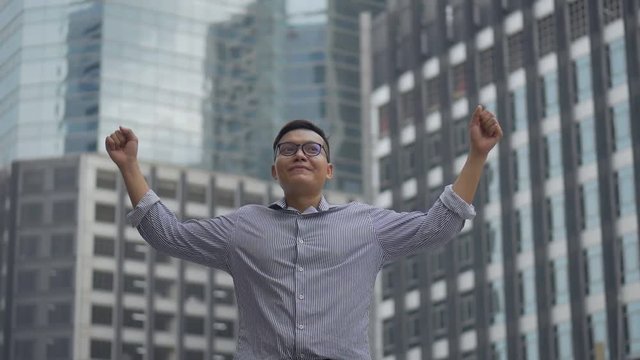 Portrait handsome asian businessman after a working have success and achievement standing looking around urban city. Slow motion low angle shoot.