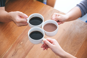 Fototapeta na wymiar Top view image of three people clinking coffee cups on wooden table in cafe