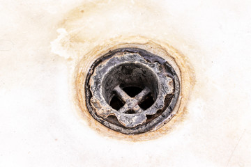 Extremely dirty bath drain mesh, hole covered with limescale or lime scale and rust close up, cleaning calcified and rusty bathroom equipment concept