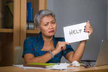 desperate and stressed attractive middle aged Asian woman holding notepad asking for help feeling...