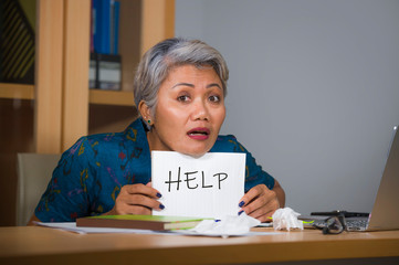 desperate and stressed attractive middle aged Asian woman holding notepad asking for help feeling...