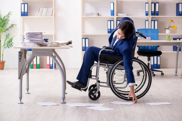 Young male employee in wheelchair working in the office 