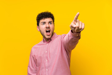 Fototapeta premium Man with curly hair over isolated yellow wall pointing away