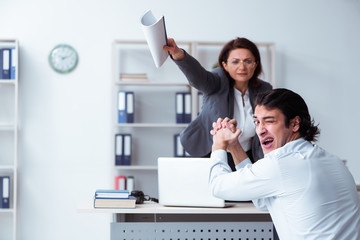 Old female boss and young male employee in the office  