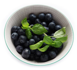 Blueberries with green basil leaves in bowl 