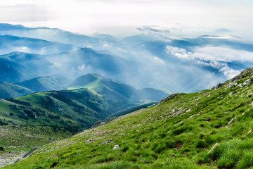 Fototapeta na wymiar Clouds onto the valley of the green mountains.