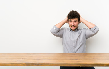Fototapeta premium Young man with a table frustrated and takes hands on head