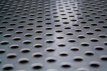 Background or texture from a gray and monophonic metal surface with symmetric and round openings.