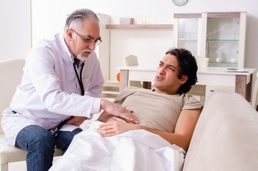 Fototapeta premium Old male doctor visiting young male patient 