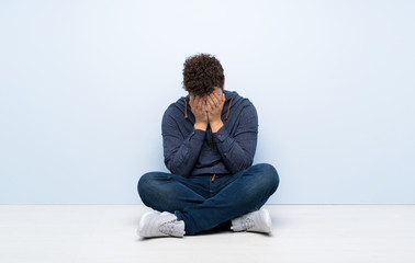 Young man sitting on the floor with tired and sick expression
